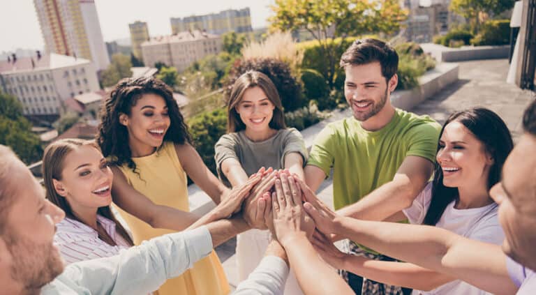 Photo of positive happy smiling co-workers holding hands together motivational team-building unit