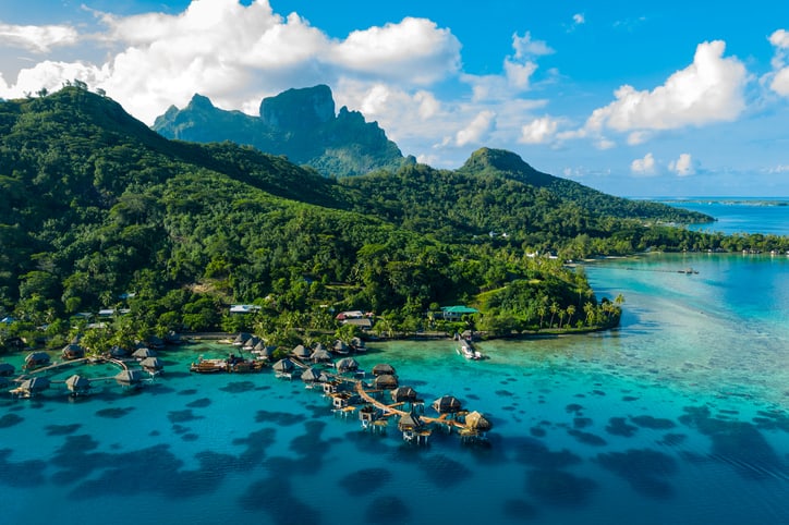 Vidéo de drone aérien de Bora Bora sur le paradis des vacances de voyage avec un complexe de luxe de bungalows sur pilotis, la plage de l'océan du lagon des récifs coralliens.