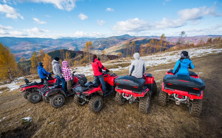 Vue arrière d'un groupe de personnes sur des quads rouges à la colline bénéficiant d'une vue dégagée sur les montagnes sous le ciel bleu en automne