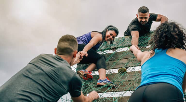 Participantes en la red de escalada de una carrera de obstáculos durante un evento corporativo de team building deportivo.