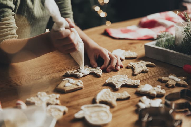 Préparation des repas de Noël. Cuisson du pain d'épices, décoration de biscuits fraîchement sortis du four avec du glaçage et du mastic.