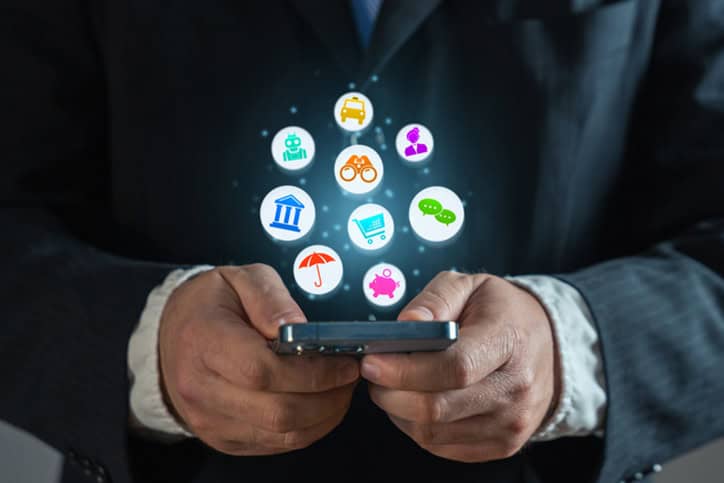 Gros plan des mains d’un homme tenant et utilisant un smartphone debout, naviguant sur Internet