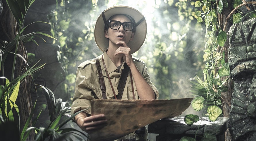 Femme dans une forêt tenant une carte pour représenter un team building aventure