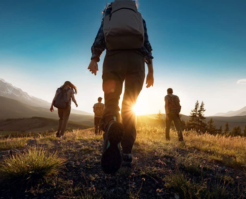 Un groupe de sportifs se promène dans les montagnes au coucher du soleil avec des sacs à dos