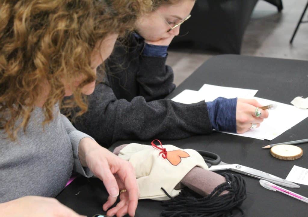 Two women make a rag doll for a team-building activity