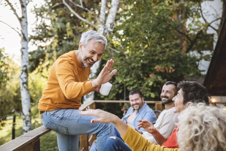 Des personnes d'âge mûr profitent de leur jardin, souriantes et détendues. Des amis plaisantent et se donnent à fond pour la bonne humeur.