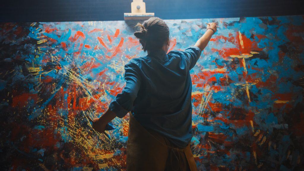 Woman painting a large colorful canvas