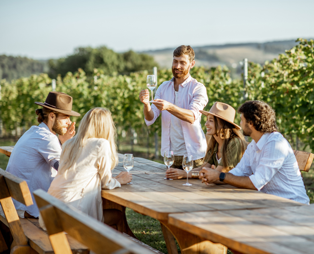 Amis buvant du vin à la table à manger sur le vignoble