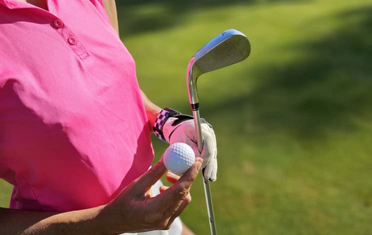 Le joueur de golf se prépare à swinguer avec le club et la balle lors d’une journée ensoleillée sur le concept de green