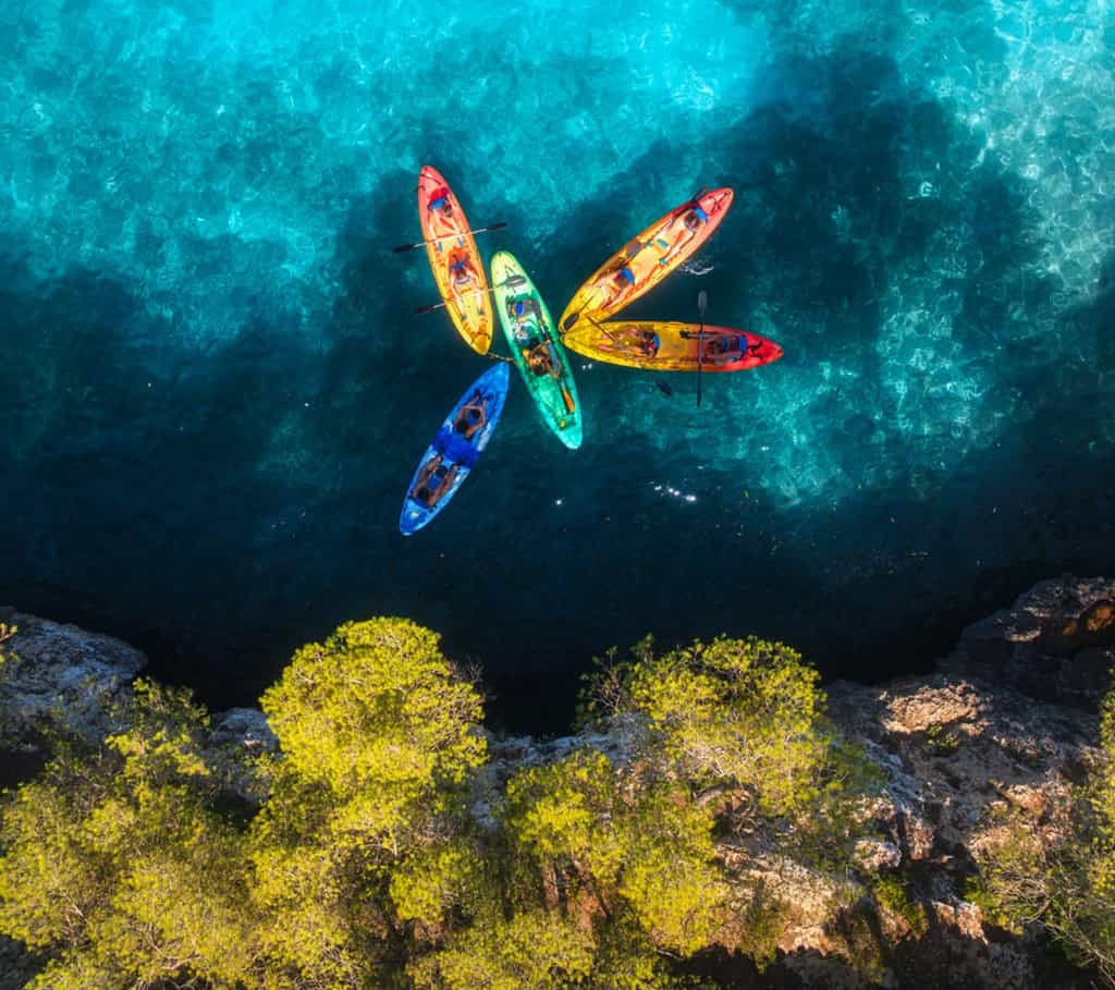 ue aérienne par drone de kayaks colorés avec des personnes sur la mer bleue lors d'un team building en été.