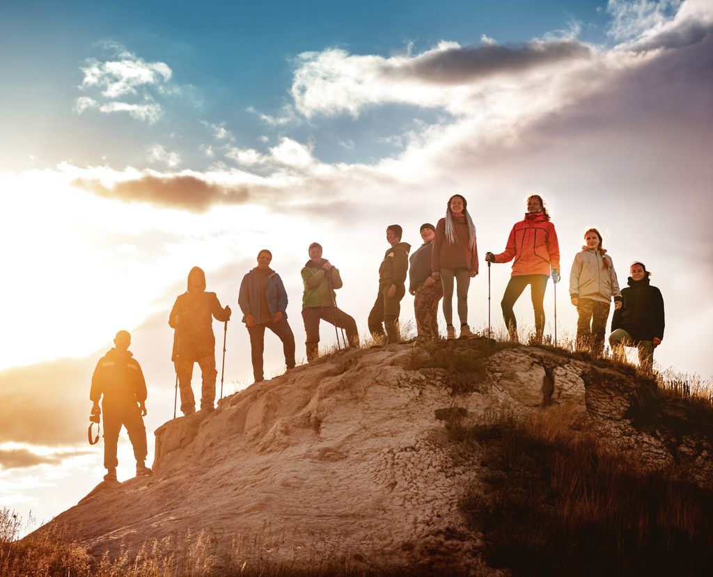Large group of hikers against the sunset during a team-building event in a nature park.