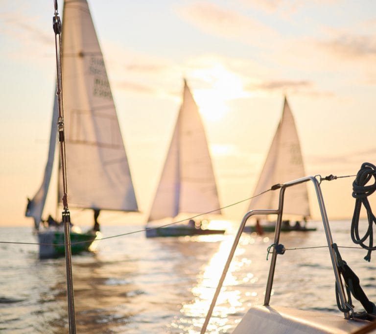 Régate de voile en méditérranée au coucher du soleil, quelques voiliers en compétition dans une course.