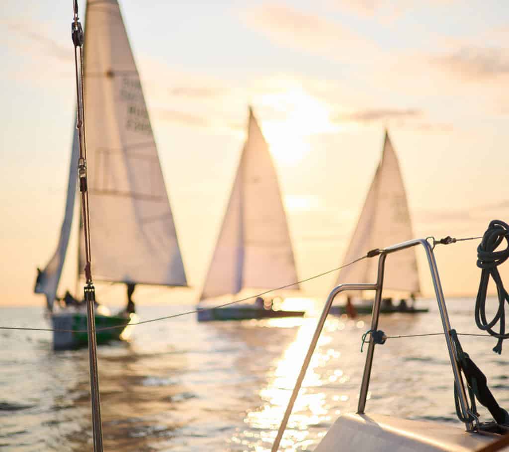 Régate de voile en méditérranée au coucher du soleil, quelques voiliers en compétition dans une course.
