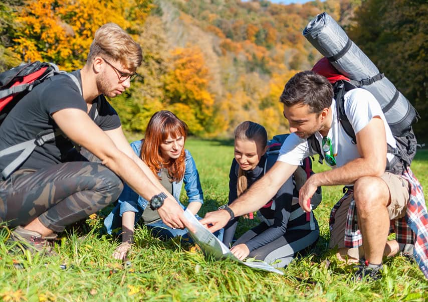 Groupe de randonneurs avec des sacs à dos regardant la carte et planifiant davantage de sentier de trekking